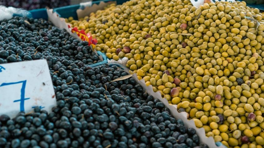 A vibrant selection of black and green olives at an outdoor market stall.