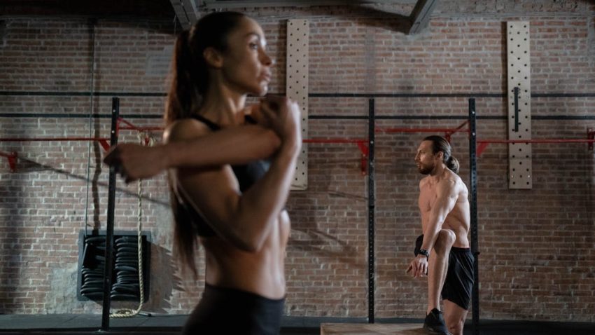 Two athletes warming up in an industrial-style gym, preparing for an intense workout session.